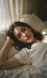 a woman laying down in a bed and looking at the camera