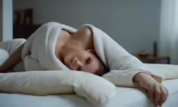 a woman is laying in bed under a towel