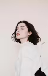the model wears white sweater with black shoulder bag and holds a cigarette