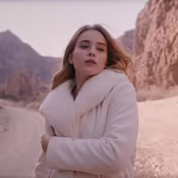 a woman standing next to a mountain and looking back