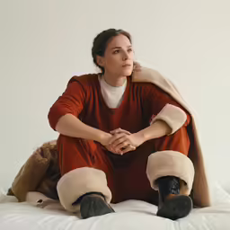a woman sitting on top of a bed covered in animals