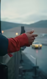 the person is pointing at the street while in the rain