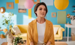 a woman posing in front of a couch with balloons all around her