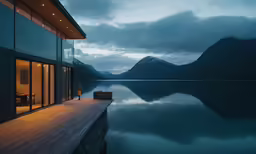 a deck is lit up in front of the glass walls of a house