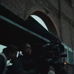 a woman is holding a video camera in front of a person