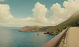 an empty road that goes along a steep cliff near the sea
