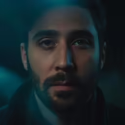 a man with a beard standing in the dark