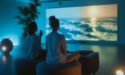two women sitting on stools in front of television