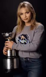 a girl in grey sweater with trophy posing for camera