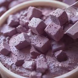 a cup filled with ice cream and chunks of pink candy
