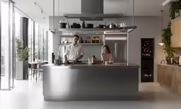 there is a man and a woman standing at the counter in the kitchen