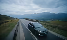 the cars drives down the road in front of a mountain