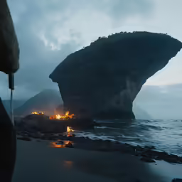 a person standing on the shore of a body of water with lit up rocks