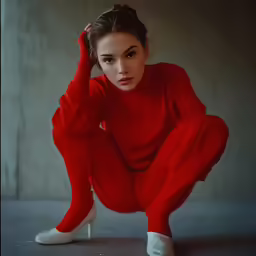 a young woman with her hands in her hair crouching down on the floor