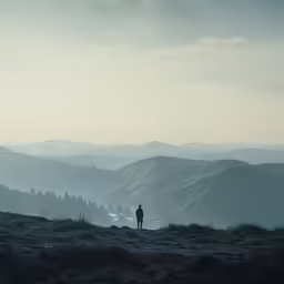 silhouette of man overlooking scenic scenic hilly area