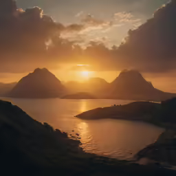 sun setting over the mountains next to a large body of water