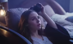 the woman lies in bed with her hair styled up