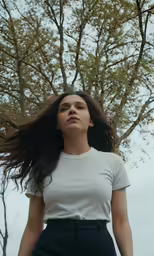 a woman standing outside wearing white shirt and black pants