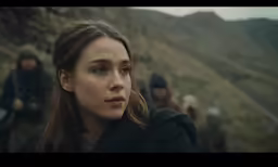 a beautiful woman looks into the distance as other men and women walk along
