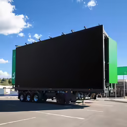 a green and black truck parked next to a gas station