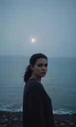 a woman standing on top of a rocky beach