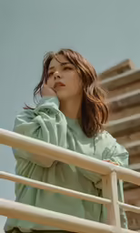 woman in green standing on rail with her hands on the nose