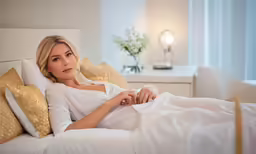 a woman in bed under a blanket and pillows