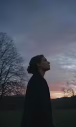 a young woman staring into the sky during a sunset