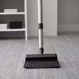 a dust mop on the floor with a metal broom