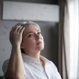 woman sitting in a chair while adjusting her hair