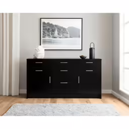 black sideboard with a white vase and a poster on the wall above