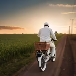 man riding on a motor cycle on a country road at sunset