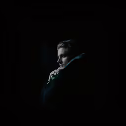a man is standing in the dark looking away