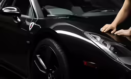 the back end of a black sports car with reflection on it