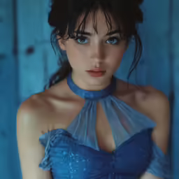 woman with blue top standing against blue wood