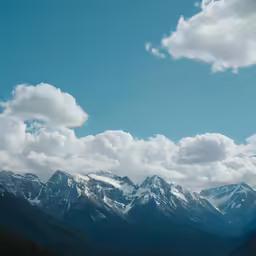 several snow capped mountains in the distance with some clouds