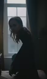 a girl sitting on a bed near a window