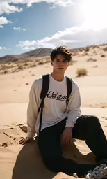 a boy sitting on the sand with a back pack