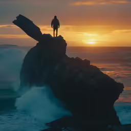 person standing on the edge of a rock formation with sunset over the ocean
