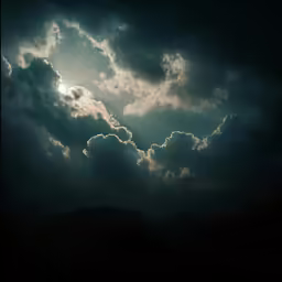 some very large clouds in the sky near some mountains