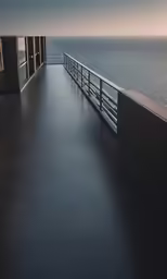 a long walkway leads to a building and the ocean