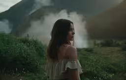 a woman stands with her back turned and her face obscured in smoke
