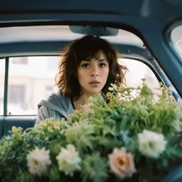 a woman sitting inside the back seat of a car with flowers in her lap