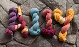four skeins of brightly colored yarn sitting on top of rock