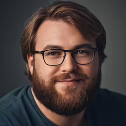 a man in glasses smiles for a photo