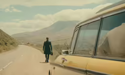 a man standing next to a yellow car