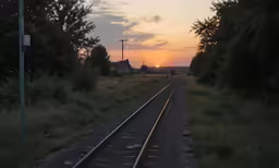 the sun rises as the sun sets on a train track