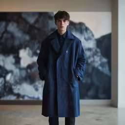 a male model in blue trench coat and dark pants