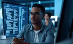 man in glasses sitting with others in the background