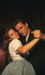 young woman in high dress standing by young man